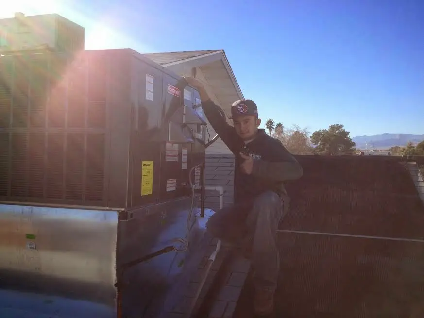 HVAC technician performing Air Duct Repair on a rooftop unit in Guilford